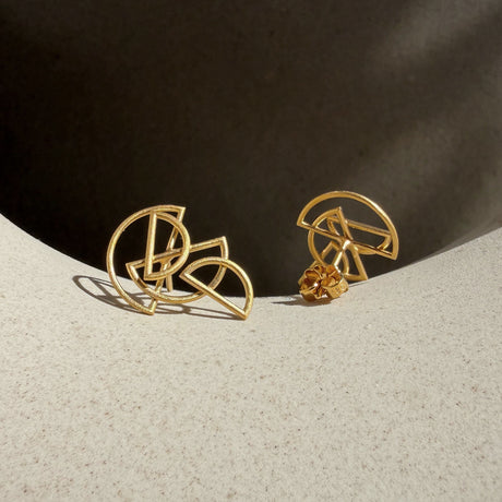 A pair of gold geometric stud earrings with an abstract, interlocking circular design, by contemporary jewellery designer, Sarah Straussberg