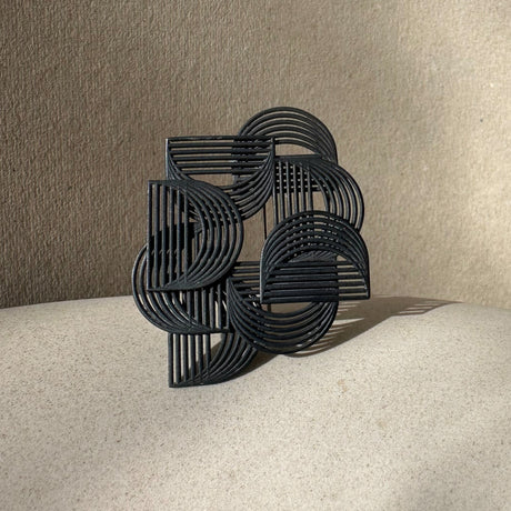 A black, oxidised sterling silver brooch with a geometric pattern, displayed against a neutral background. By contemporary jewellery designer, Sarah Straussberg