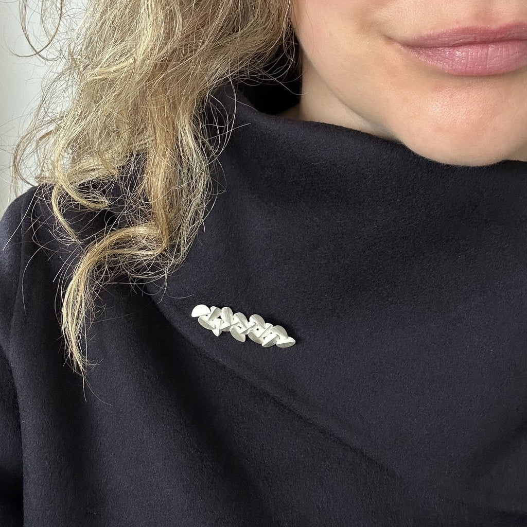 Sculptural silver brooch photographed on model  by contemporary jewellery designer, Sarah Straussberg 
