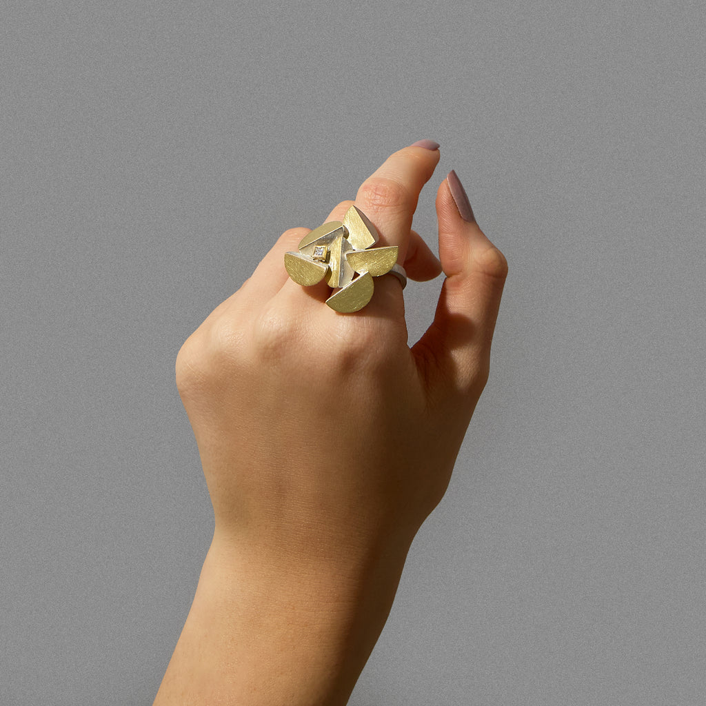 A sculptural ring featuring a princess cut ocean diamond set in a geometric, mixed metal design, shown on model. By contemporary jewellery designer, Sarah Straussberg