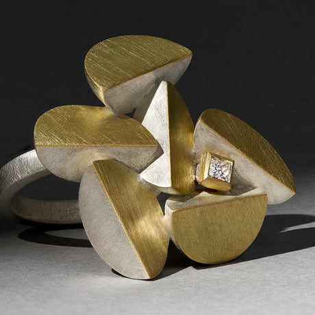 A sculptural ring featuring a princess cut ocean diamond set in a geometric, mixed metal design. By contemporary jewellery designer, Sarah Straussberg