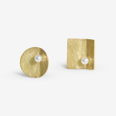 A pair of asymmetric pearl earrings with one earring round and one earring square, both with a pearl and handcrafted from 18ct yellow gold with a brushed matte finish. By contemporary jewellery designer, Sarah Straussberg