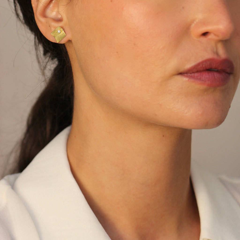 A modern square 18ct gold pearl earring  18ct yellow gold with a brushed matte finish photographed on model. By contemporary jewellery designer, Sarah Straussberg
