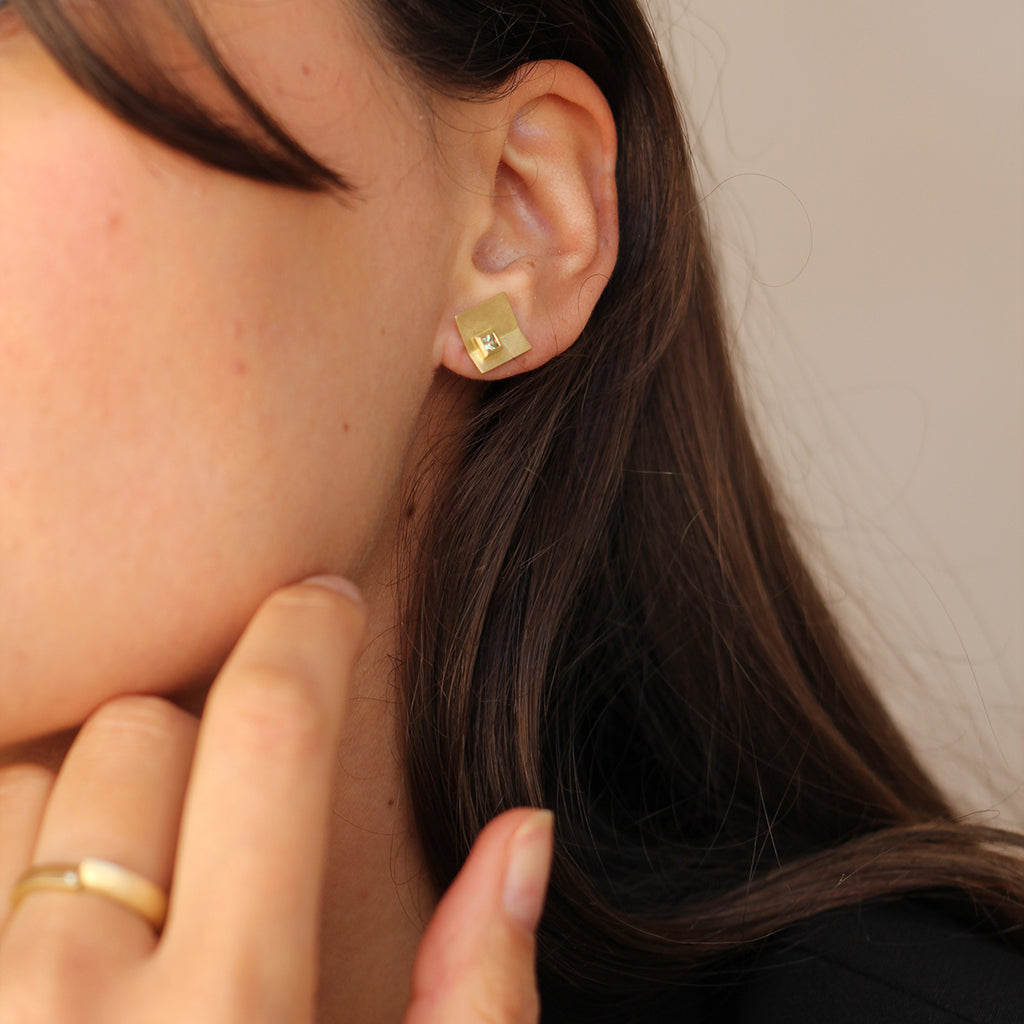 An 18ct square gold sapphire earring shown on model by contemporary jewellery designer, Sarah Straussberg