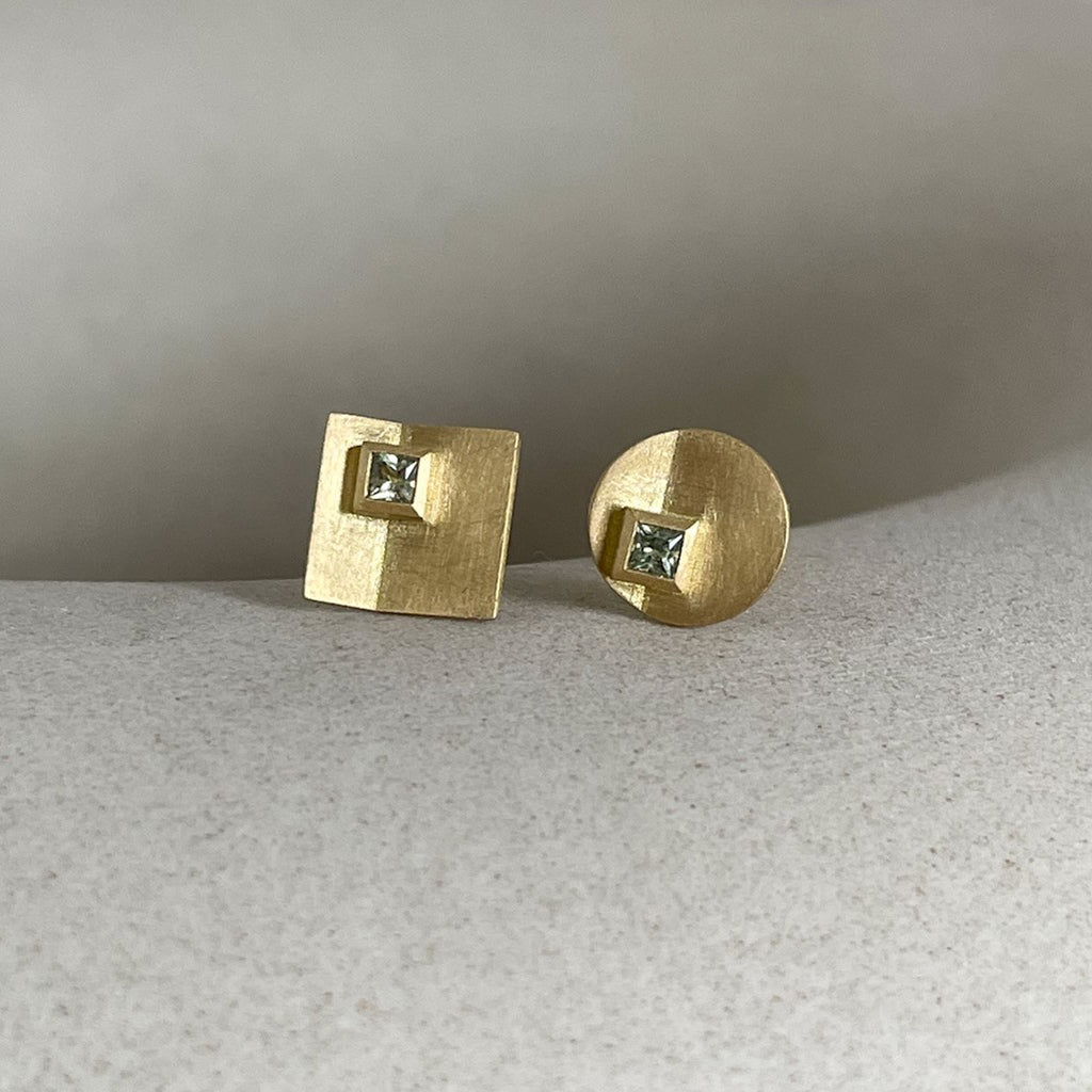 Asymmetric 18ct gold sapphire earrings on grey background by contemporary jewellery designer, Sarah Straussberg