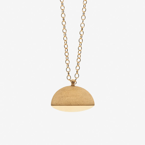 A gold pendant necklace with a brushed finish. The pendant has a semi-circular shape, by contemporary jewellery designer, Sarah Straussberg